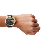 Diesel Armbanduhr mit schwarzem Zifferblatt mit gold-weißen Indizes, Chronographenwerk, goldenem Gehäuse und schwarzem Lederband; Tragebild