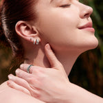 Eine Frau genießt mit geschlossenen Augen das Sonnenlicht. Sie trägt Ania Haie Ohrringe - Silver Kiss Hoops und einen schimmernden 925 Sterling Silber Ring mit Zirkonoxid.