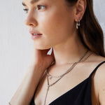 Eine Frau in einem schwarzen Oberteil trägt das Echtzeit Armband - The Glitter One von Echtzeit, überlagert mit anderem 925er Sterling Silber Schmuck, und schaut mit der Hand im Nacken zur Seite.