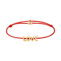 Das Echtzeit Armband - Love Letters von Echtzeit: rotes Stoffband mit goldenen LOVE Buchstabenanhängern und verstellbarem Verschluss - das perfekte Geschenk für besondere Anlässe.