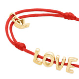 Das Echtzeit Armband - Love Letters von Echtzeit: Rotes Stoffband mit goldenen "LOVE" Buchstaben und Herz-Charm - ein liebevolles Geschenk für jeden Anlass.