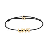 Das Echtzeit Armband - Love Letters von Echtzeit besteht aus einem schwarzen Stoffband mit goldenen LOVE Buchstaben und einer goldenen Schließe, die auf einem weißen Hintergrund abgebildet sind.
