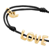 Das Echtzeit Armband - Love Letters von Echtzeit besteht aus schwarzem Stoffband mit goldenen LOVE-Buchstaben und einem kleinen goldenen Anker-Charm.