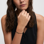 Echtzeit Armband Love Letters – filigranes schwarzes Kordelarmband mit goldenem LOVE-Schriftzug, getragen am Handgelenk