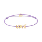 Das Echtzeit Armband - Love Letters von Echtzeit kombiniert ein lavendelfarbenes Stoffarmband mit goldenen LOVE-Buchstaben und Herzanhänger - ein bezauberndes Geschenk.