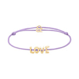Das Echtzeit Armband - Love Letters von Echtzeit kombiniert ein lavendelfarbenes Stoffarmband mit goldenen LOVE-Buchstaben und Herzanhänger - ein bezauberndes Geschenk.