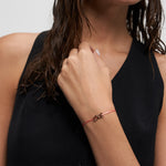 Echtzeit Armband Love Letters – filigranes rosa Kordelarmband mit roségoldenem LOVE Schriftzug, getragen am Handgelenk