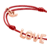 Das Echtzeit Armband - Love Letters von Echtzeit besteht aus einer dunkelroten Kordel mit goldenen LOVE-Buchstaben und einem goldenen Herz - ein Geschenk, das von Herzen kommt.