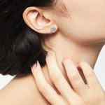 Eine Frau mit kurzen dunklen Haaren trägt den LIEBESKIND BERLIN Ohrstecker - The Iconic Geometric von Liebeskind Berlin in minimalistischem Design.