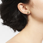 Nahaufnahme einer Person mit kurzen dunklen Haaren, die einen kleinen goldenen LIEBESKIND BERLIN Ohrstecker - Keep Loving von Liebeskind Berlin trägt, ideal für einen dezenten Ear Candy Style.