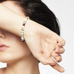 Eine Frau mit kurzen dunklen Haaren bedeckt ihre Augen mit ihrem Arm und zeigt das LIEBESKIND BERLIN Beads - The Blue Beads Armband von Liebeskind Berlin an ihrem Handgelenk.