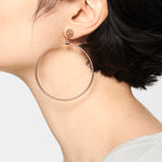 Nahaufnahme des Ohrs einer Person, die Liebeskind Berlin Creole - The Retro One, große dünne Creolen trägt, wobei kurzes dunkles Haar zu sehen ist.