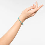 Eine Hand trägt das Liebeskind Berlin Beads - The SmallTurquoise Armband mit schlichten türkisfarbenen Perlen vor einem schlichten weißen Hintergrund.