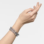 Eine mit zwei Perlenarmbändern geschmückte Hand mit den LIEBESKIND BERLIN Beads - The Big Moonstone von Liebeskind Berlin, anmutig posiert vor weiß-elegantem Schmuck für Damen in einer zeitlosen Aufnahme.