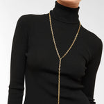 Person, die einen schwarzen gerippten Rollkragenpullover und die Liebeskind Berlin Halskette - The Long Pearl vor einem schlichten Hintergrund trägt.