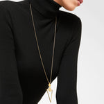 A person in a black ribbed turtleneck wears the LIEBESKIND BERLIN Halskette – The Geometric, featuring a polished stainless steel geometric pendant. The lower face, neck, and upper body are visible, giving off a subtle 70s vibe.