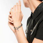 Liebeskind Berlin Armband bestehend aus einer silbernen, groben Gliederkette und einem Herzanhänger mit grafischen Elementen; Tragebild