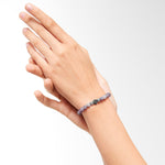 Eine Hand trägt die LIEBESKIND BERLIN Beads - The Purple Quartz von Liebeskind Berlin, während eine andere Hand sanft das Handgelenk berührt.