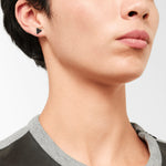 Nahaufnahme einer Person, die den LIEBESKIND BERLIN Ohrstecker - The Geometric von Liebeskind Berlin in Schwarz trägt und diesem trendigen Ohrring einen 70er-Jahre-Touch verleiht.