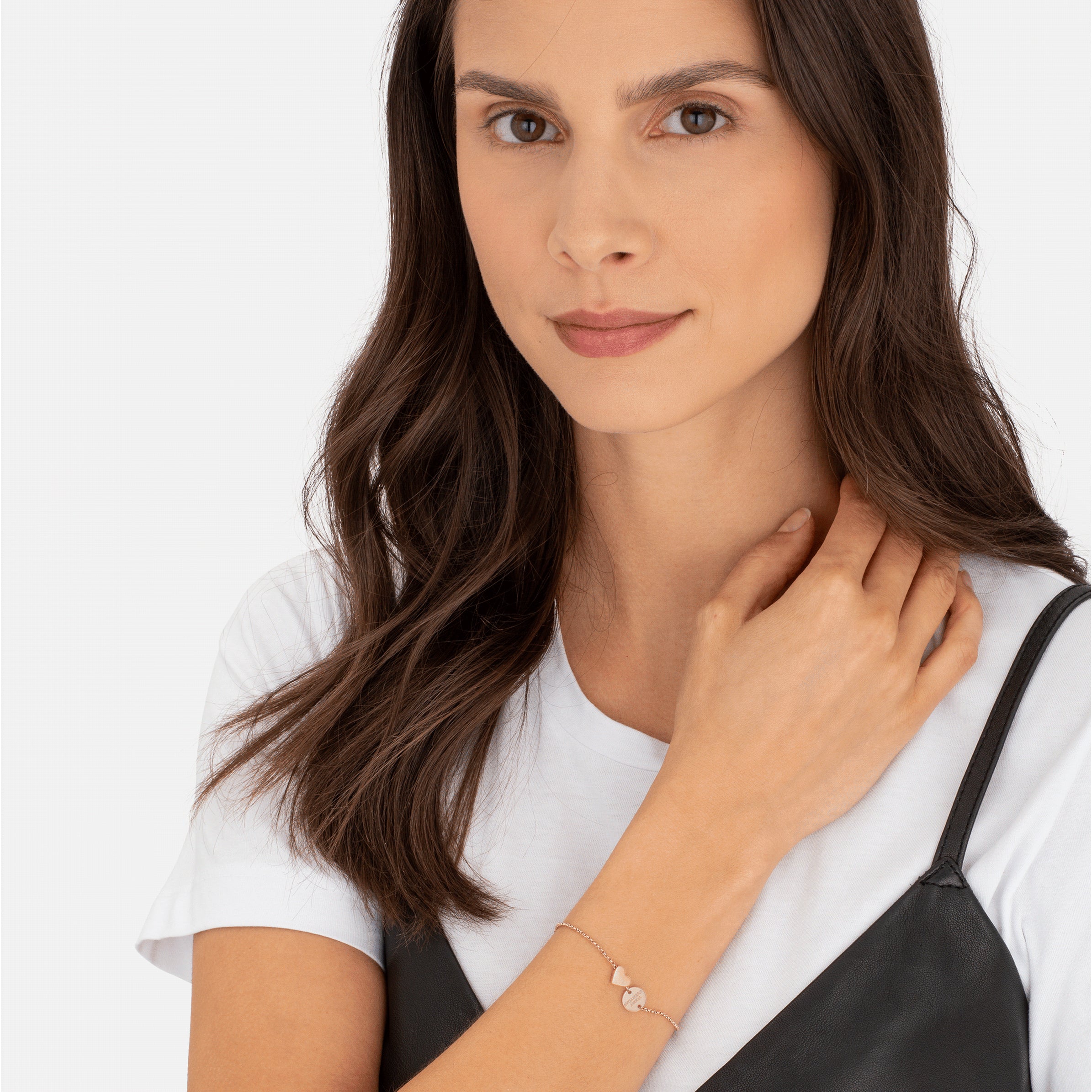 Frau mit langen braunen Haaren, die ein weißes T-Shirt, ein schwarzes Oberteil und das Armband LIEBESKIND BERLIN Set - Together Forever von Liebeskind Berlin trägt und in die Kamera schaut.