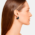 Frau mit glattem braunem Haar trägt LIEBESKIND BERLIN Ohrstecker - The Mirror von Liebeskind Berlin, im Profil vor weißem Hintergrund. Minimalistischer Damen Schmuck für einen modernen Look.