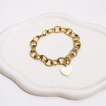 Goldfarbenes Gliederarmband von Liebeskind Berlin mit herzförmigem Anhänger, auf dessen Rand LIEBESKIND BERLIN geprägt wurde; Zusatzbild auf Tablet