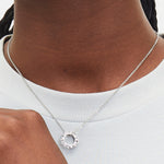 Liebeskind Berlin Halskette bestehend aus einer silbernen Ankerkette und einem silbernen, runden Anhänger mit 3D Schriftzug; Tragebild