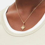 Goldener Liebeskind Berlin Charm mit drehbarem Plättchen, graviertem Wassermann-Zodiac-Symbol auf der einen und Logoschriftzug auf der anderen Seite; Tragebild