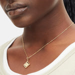 Goldener Liebeskind Berlin Charm mit drehbarem Plättchen, graviertem Widder-Zodiac-Symbol auf der einen und Logoschriftzug auf der anderen Seite; Tragebild