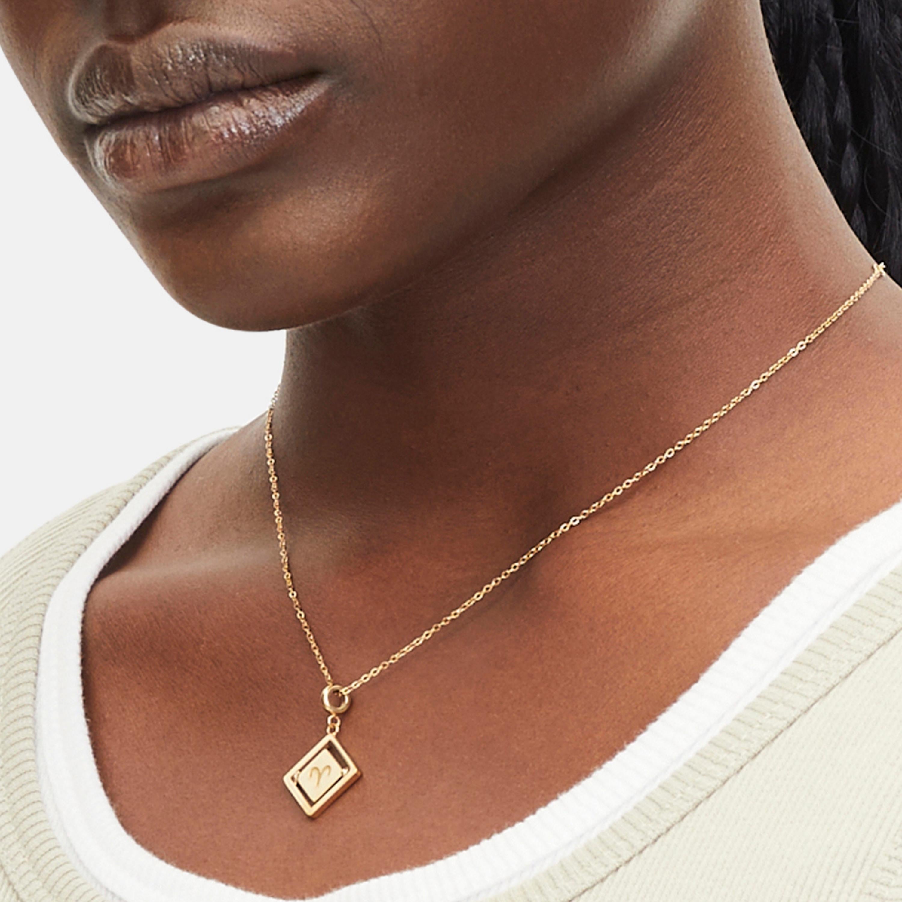 Goldener Liebeskind Berlin Charm mit drehbarem Plättchen, graviertem Widder-Zodiac-Symbol auf der einen und Logoschriftzug auf der anderen Seite; Tragebild