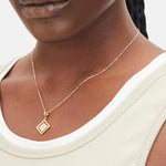 Goldener Liebeskind Berlin Charm mit drehbarem Plättchen, graviertem Skorpion-Zodiac-Symbol auf der einen und Logoschriftzug auf der anderen Seite; Tragebild