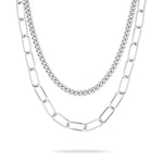 Das LIEBESKIND BERLIN Halsketten-Set - The Layering von Liebeskind Berlin besteht aus zwei silbernen Ketten mit kleinen Panzergliedern und einem eleganten Büroklammer-Stil - ideal für mühelose Lagenlooks auf weißem Hintergrund.