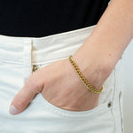 Eine Hand in der Tasche einer weißen Jeans, die LIEBESKIND BERLIN Armband - The Must-Have by Liebeskind Berlin trägt, vor einem schwarzen Top.