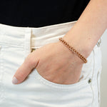 Eine Hand, die das LIEBESKIND BERLIN Armband - The Must-Have by Liebeskind Berlin trägt, ruht in der Tasche einer weißen Jeans vor einem schwarzen Hemd.