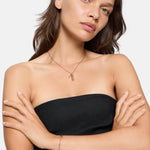 Frau in einem schwarzen trägerlosen Oberteil mit verschränkten Armen, trägt die Liebeskind Berlin Love Lock Halskette und ein Armband und schaut in die Kamera.