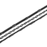 Die LIEBESKIND BERLIN Fußkette - Sparkling With Layers von Liebeskind Berlin ist diagonal auf weißem Grund mit drei schwarzen Metallketten abgebildet, von denen jede einzelne Glieder für einen eleganten Lagenlook aufweist.