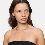 Frau trägt ein schwarzes trägerloses Oberteil und die LIEBESKIND BERLIN Halskette - Sparkling With Layers von Liebeskind Berlin und schaut zur Seite.