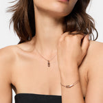 Frau trägt ein trägerloses schwarzes Oberteil und ein Armband, beides gestylt mit der LIEBESKIND BERLIN Halskette - The Festive Mini Link Sparkle, jeweils verziert mit funkelnden Zirkoniasteinen.