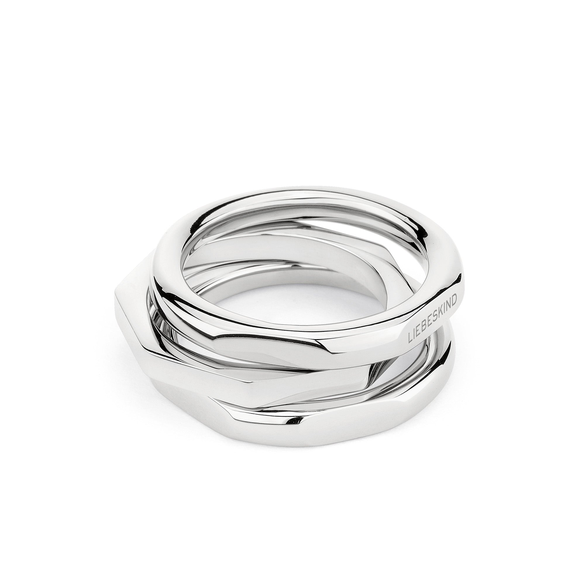 Der LIEBESKIND BERLIN Ring - Urban Chic in Größe 56 besteht aus drei ineinander verschlungenen Silberringen, von denen einer mit Liebeskind Berlin graviert ist. Sie bilden ein auffälliges Ensemble auf weißem Hintergrund.