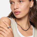 Frau mit beigem Tank-Top und Silberschmuck trägt den LIEBESKIND BERLIN Ring - Urban Chic in 58 von Liebeskind Berlin und blickt mit neutralem Blick zur Seite.