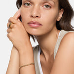 Frau mit hellbraunem Haar trägt einen Liebeskind Berlin Urban Chic Ring in Größe 54 und stützt ihr Kinn auf ihre Hand.