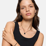 Frau mit hellbraunem Haar, schwarzem Tanktop und Halskette posiert mit einem gekreuzten Arm und trägt das Liebeskind Berlin Armband - Bead Mix.