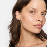 Frau mit hellbraunem Haar trägt ein schwarzes Oberteil und LIEBESKIND BERLIN Creole - The Mini Link Ohrringe von Liebeskind Berlin und schaut in die Kamera.