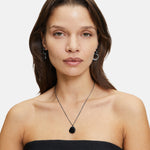 Frau mit glattem braunem Haar, trägt ein schwarzes trägerloses Top, silberne Ohrringe und die LIEBESKIND BERLIN Halskette - The Organic Pendant von Liebeskind Berlin.