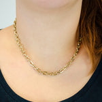 Eine Frau trägt die LIEBESKIND BERLIN Halskette - The Double Tag von Liebeskind Berlin und ein dunkles Oberteil, ihr Haar fällt über eine Schulter, betont eleganten Schmuck.