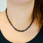 Eine Person trägt die LIEBESKIND BERLIN Halskette - The Double Tag von Liebeskind Berlin mit einem dunklen Hemd, das vom Hals bis zu den Schultern reicht - eine subtile Anspielung auf den modernen Damen Schmuck Stil.