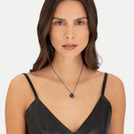 Braunhaarige Frau mit schwarzem ärmellosen Top trägt die LIEBESKIND BERLIN Halskette - Together, Today, Everyday von Liebeskind Berlin, eine elegante runde Halskette mit Anhänger, die sich perfekt als Geschenk eignet und in die Kamera schaut.