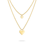 Zwei goldene LIEBESKIND BERLIN Halsketten von Liebeskind Berlin, eine mit rundem Anhänger und eine mit Herzanhänger aus hochwertigem Edelstahl auf weißem Hintergrund.