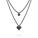 LIEBESKIND BERLIN Halskette - Layered Love: Zweigliedrige Edelstahlkette von Liebeskind Berlin mit schwarzem Kreis- und Herzanhänger auf weißem Hintergrund.