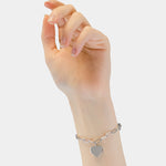 Eine Hand trägt das Liebeskind Berlin Armband - My Heart mit einem herzförmigen Anhänger, abgebildet auf weißem Hintergrund.